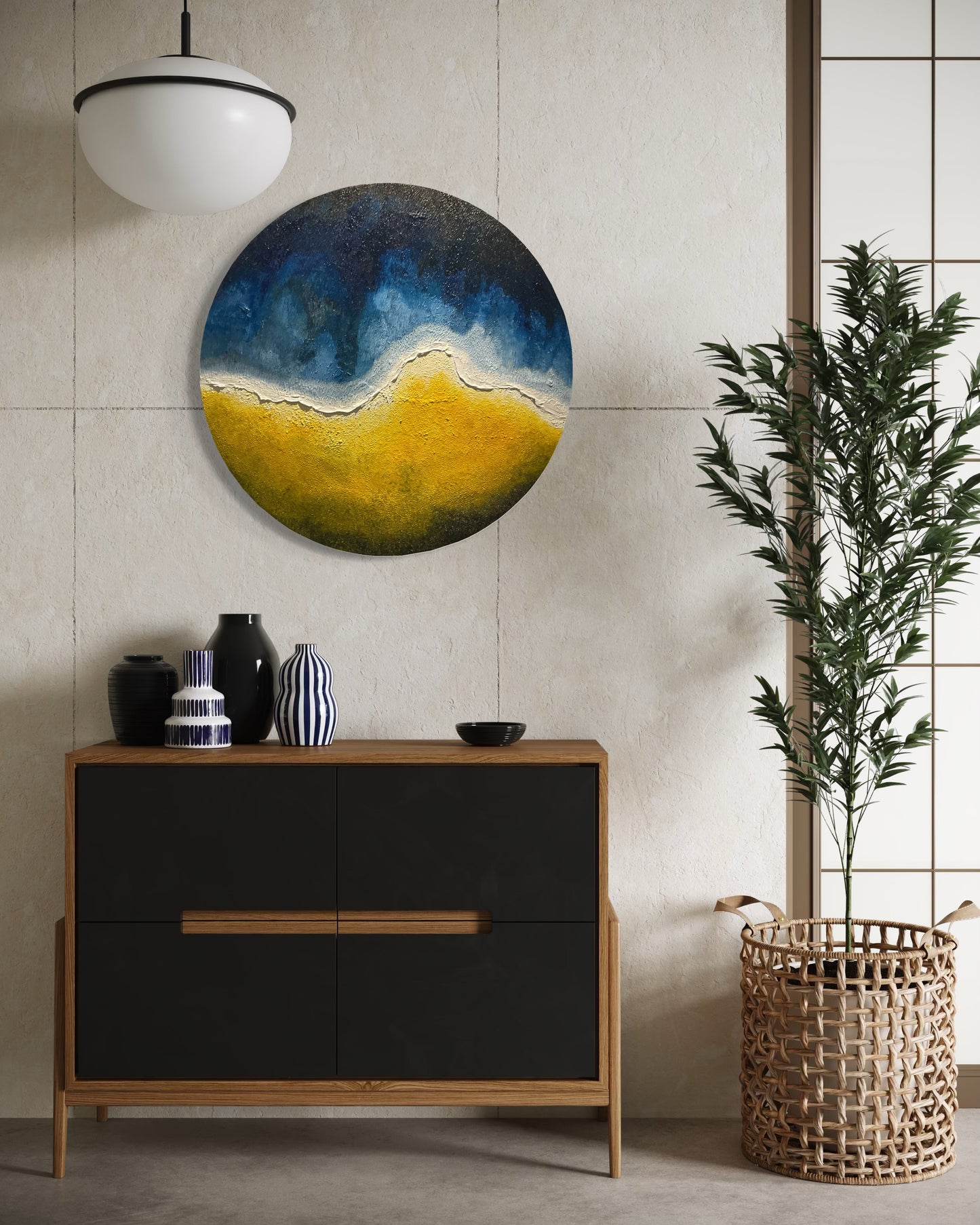Round abstract painting by Michel L’Artiste in blue, yellow, and white tones, displayed above a modern black and wood dresser with decorative vases – contemporary wall art for living spaces.