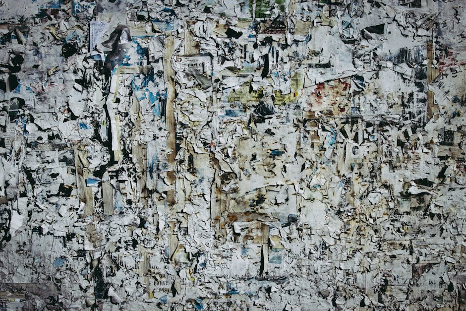 A textured wall with layers of torn and weathered paper for artistic backgrounds.