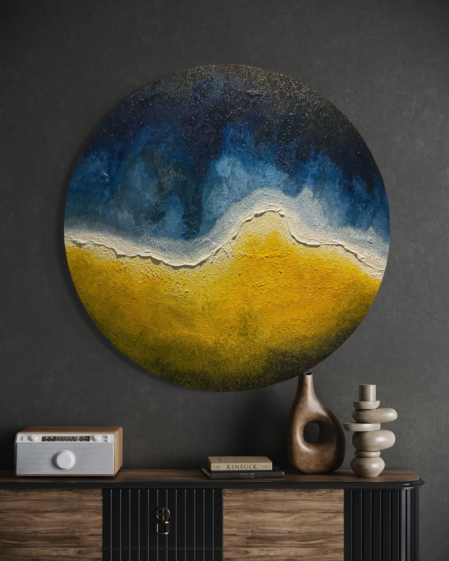 Round abstract painting by Michel L’Artiste in deep blue, white, and golden yellow tones, displayed on a dark gray wall above a modern wooden console with sculptural decor – contemporary luxury wall art.